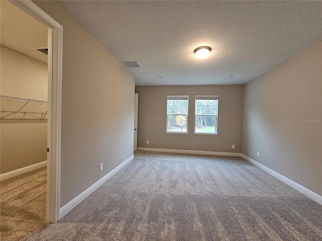 unfurnished room with carpet and a textured ceiling