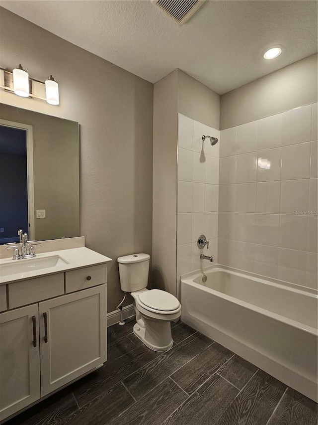 full bathroom featuring vanity, a textured ceiling, toilet, and tiled shower / bath