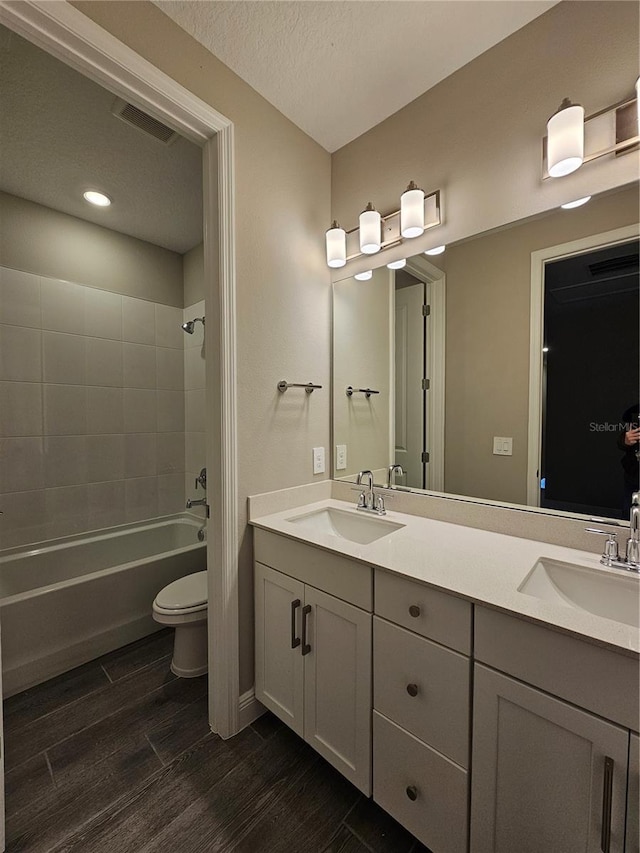 full bathroom featuring vanity, tiled shower / bath, a textured ceiling, and toilet