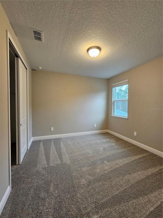 carpeted spare room featuring a textured ceiling