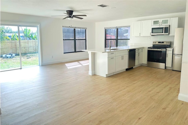 kitchen featuring stainless steel appliances, sink, white cabinets, and light hardwood / wood-style flooring