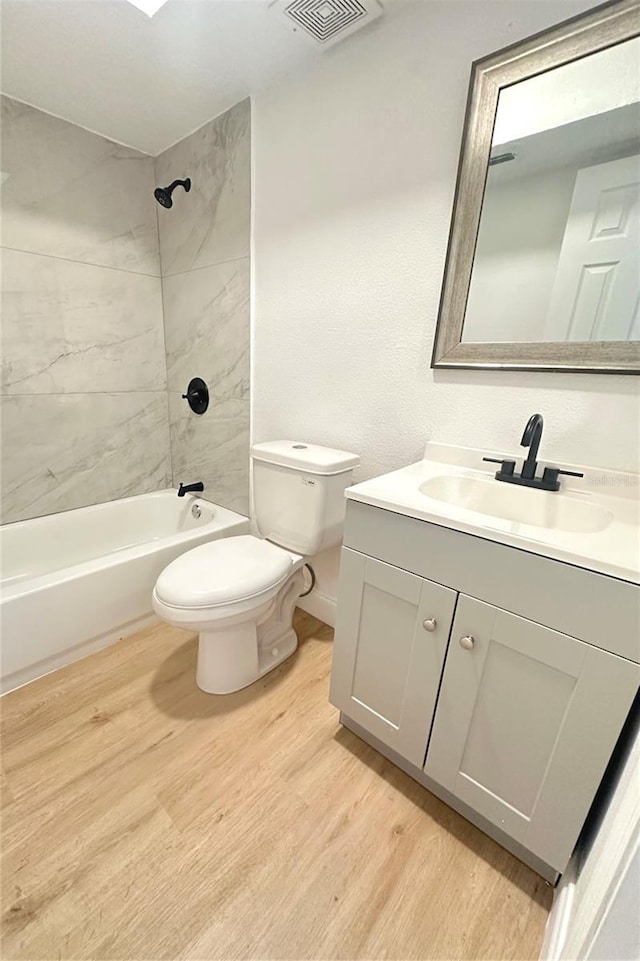 bathroom with visible vents, toilet, bathing tub / shower combination, wood finished floors, and vanity