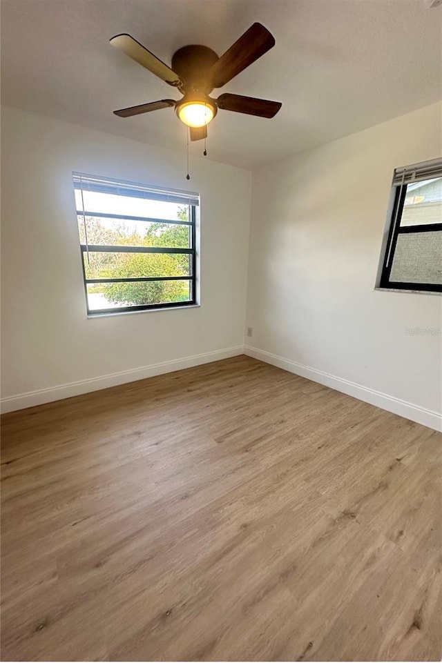 unfurnished room with light wood-type flooring, baseboards, and a ceiling fan