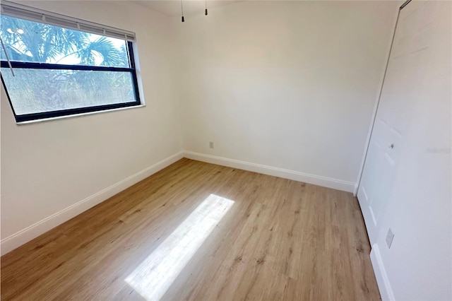 unfurnished room with baseboards and light wood-type flooring