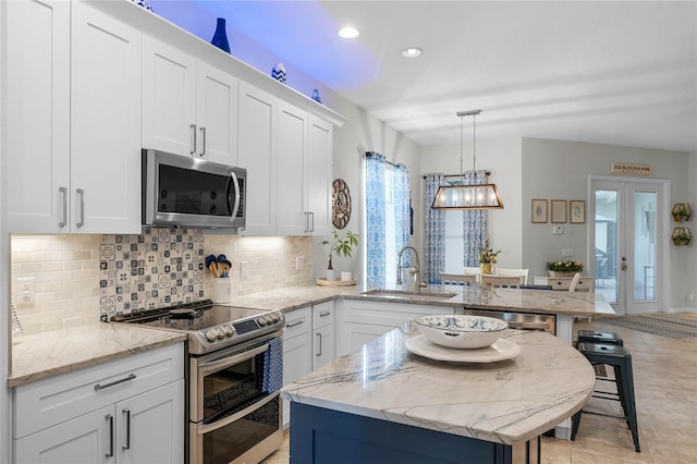 kitchen with a breakfast bar, sink, decorative light fixtures, appliances with stainless steel finishes, and white cabinets