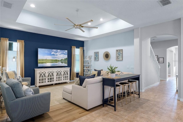 living room featuring ceiling fan and a tray ceiling