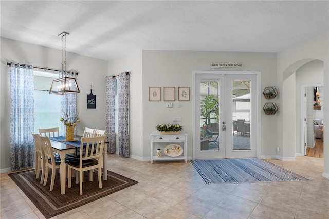 dining area with light tile patterned flooring, an inviting chandelier, a textured ceiling, and french doors