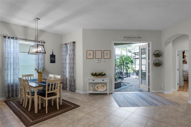 tiled dining room with a textured ceiling and a notable chandelier