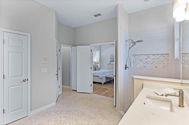 bathroom featuring vanity, tile patterned flooring, and a tile shower