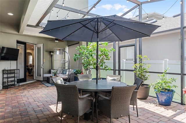 view of patio featuring ceiling fan and glass enclosure