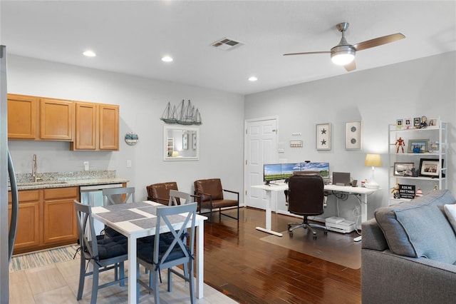 interior space featuring dishwasher, sink, ceiling fan, light stone countertops, and light wood-type flooring