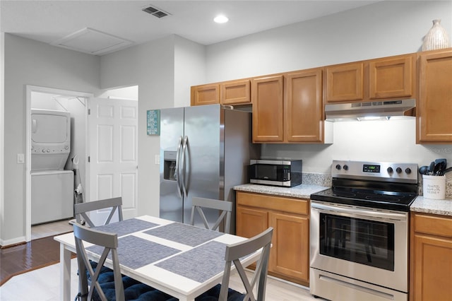 kitchen featuring stacked washer and dryer, stainless steel appliances, and light wood-type flooring