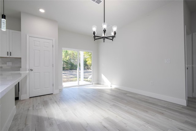 unfurnished dining area featuring a chandelier and light hardwood / wood-style floors