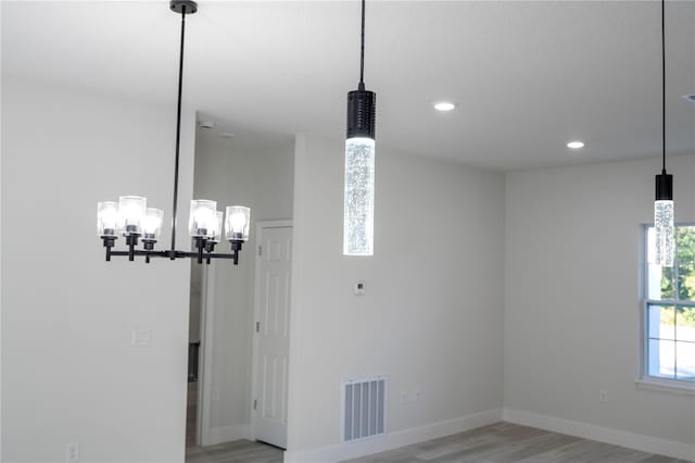 unfurnished dining area featuring a notable chandelier and light hardwood / wood-style floors