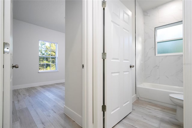 bathroom with tiled shower / bath combo, hardwood / wood-style flooring, and toilet