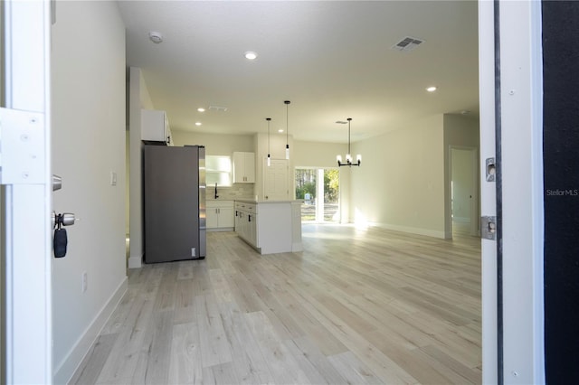 kitchen featuring stainless steel fridge, light hardwood / wood-style flooring, white cabinetry, backsplash, and a kitchen island