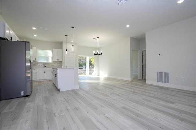 kitchen with stainless steel fridge, light hardwood / wood-style flooring, white cabinetry, a center island, and decorative light fixtures