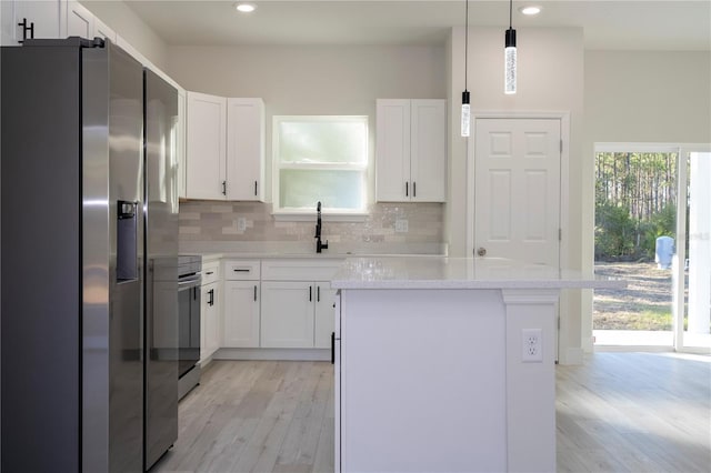 kitchen with stainless steel appliances, white cabinetry, sink, and pendant lighting