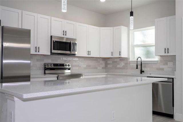 kitchen featuring sink, white cabinetry, light stone counters, hanging light fixtures, and stainless steel appliances