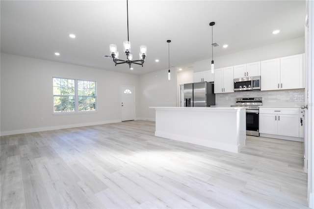 kitchen with decorative light fixtures, a center island, light wood-type flooring, stainless steel appliances, and white cabinets