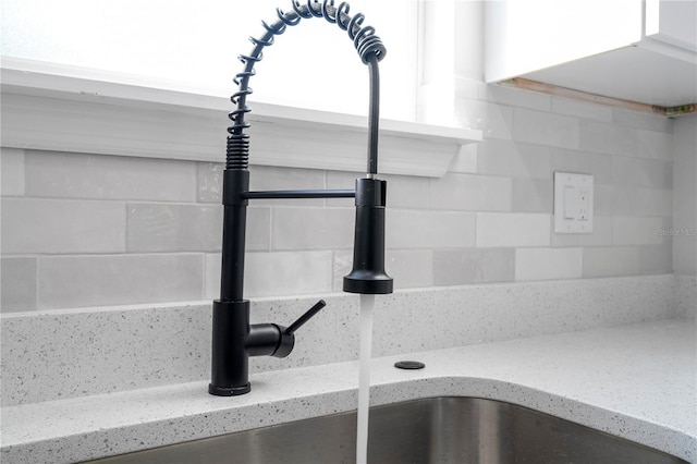 details with backsplash, light stone countertops, and sink