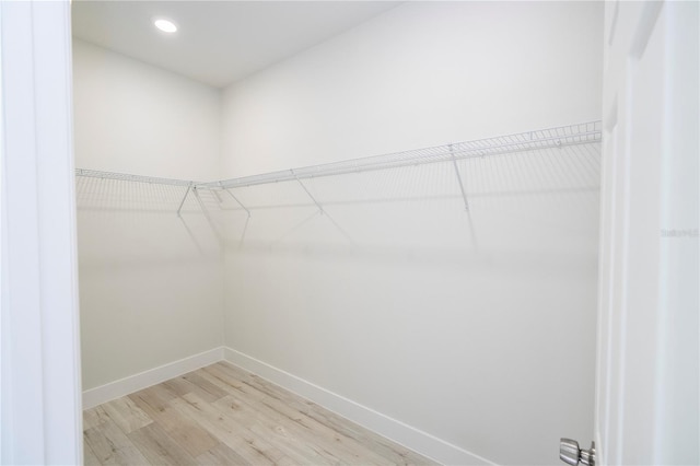 walk in closet with light hardwood / wood-style floors