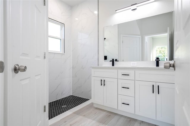 bathroom featuring hardwood / wood-style flooring, vanity, and a tile shower