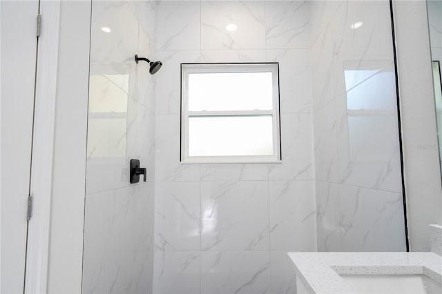 bathroom featuring tiled shower and sink