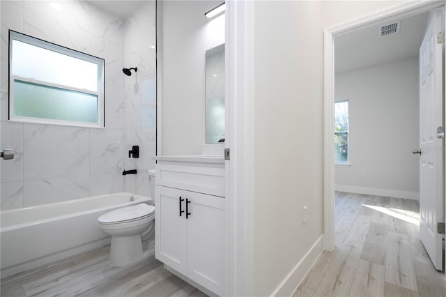 full bathroom featuring hardwood / wood-style flooring, tiled shower / bath, vanity, and toilet