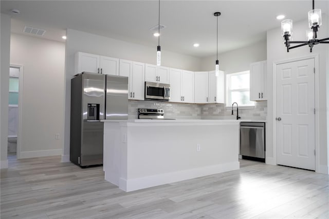 kitchen featuring hanging light fixtures, stainless steel appliances, a center island, and white cabinets