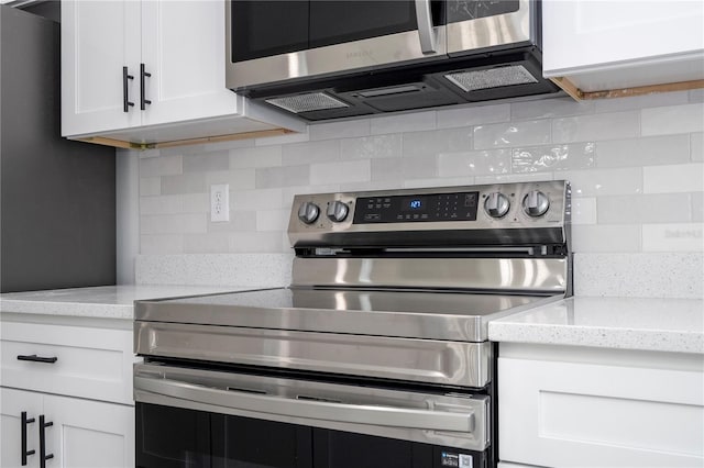 kitchen with white cabinets, light stone countertops, appliances with stainless steel finishes, and backsplash