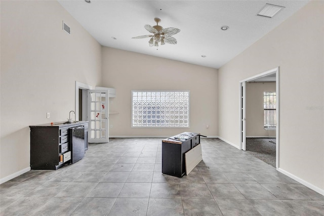 kitchen featuring light tile patterned flooring, sink, a center island, high vaulted ceiling, and ceiling fan