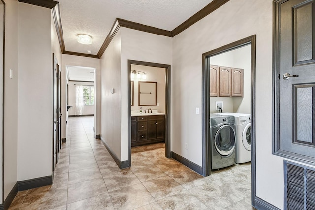 clothes washing area with sink, cabinets, ornamental molding, a textured ceiling, and separate washer and dryer