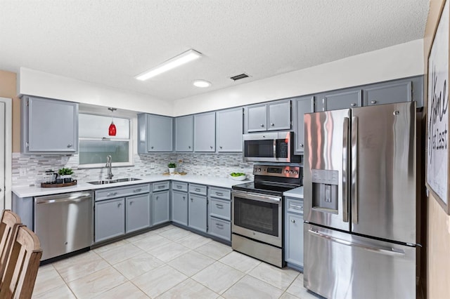 kitchen with stainless steel appliances, sink, a textured ceiling, and decorative backsplash