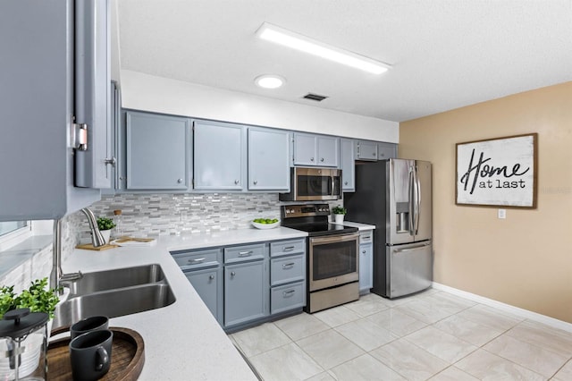 kitchen featuring tasteful backsplash, appliances with stainless steel finishes, light tile patterned flooring, and sink