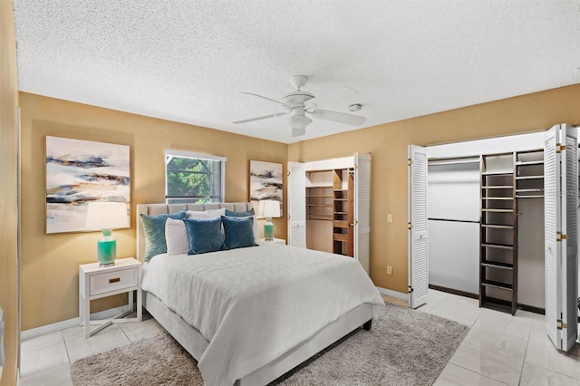 bedroom featuring two closets, a textured ceiling, ceiling fan, and light tile patterned flooring