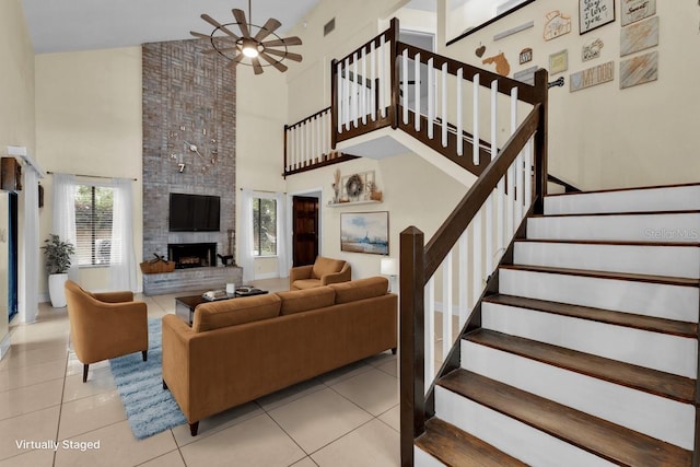 tiled living room with a high ceiling, a large fireplace, and ceiling fan