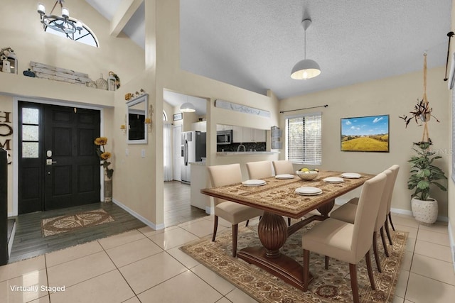 tiled dining area featuring high vaulted ceiling, a chandelier, and a textured ceiling