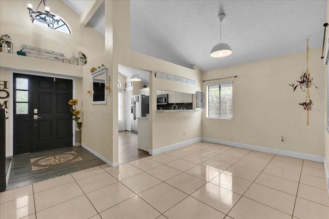 foyer entrance featuring lofted ceiling, a chandelier, light tile patterned floors, and a textured ceiling