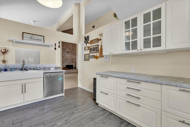 kitchen with white cabinetry, sink, light stone counters, and dishwasher