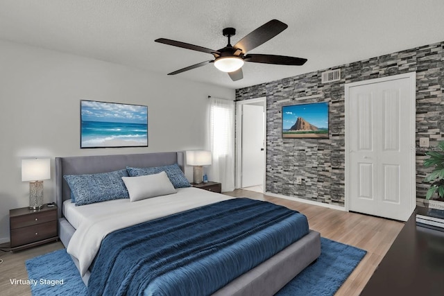 bedroom with a closet, ceiling fan, light hardwood / wood-style floors, and a textured ceiling