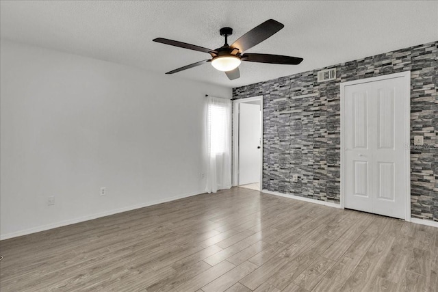 unfurnished room featuring ceiling fan, light hardwood / wood-style floors, and a textured ceiling