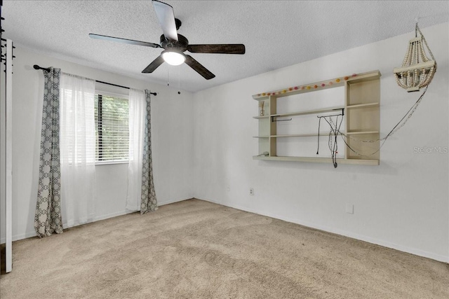 empty room featuring ceiling fan, a textured ceiling, and carpet flooring