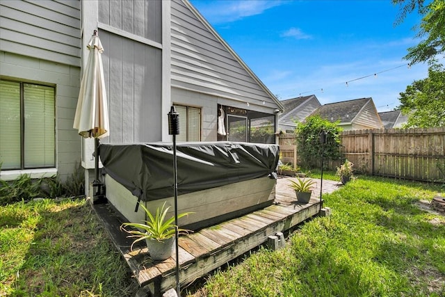 wooden deck featuring a jacuzzi and a lawn