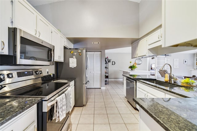 kitchen featuring stainless steel appliances, dark stone countertops, light tile patterned floors, and white cabinets