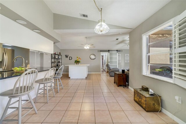 kitchen with vaulted ceiling, a barn door, and a kitchen breakfast bar