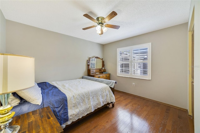 bedroom featuring dark hardwood / wood-style flooring, ceiling fan, and a textured ceiling