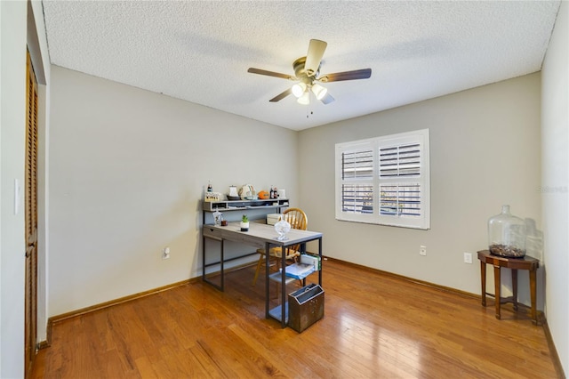 home office with ceiling fan, hardwood / wood-style floors, and a textured ceiling