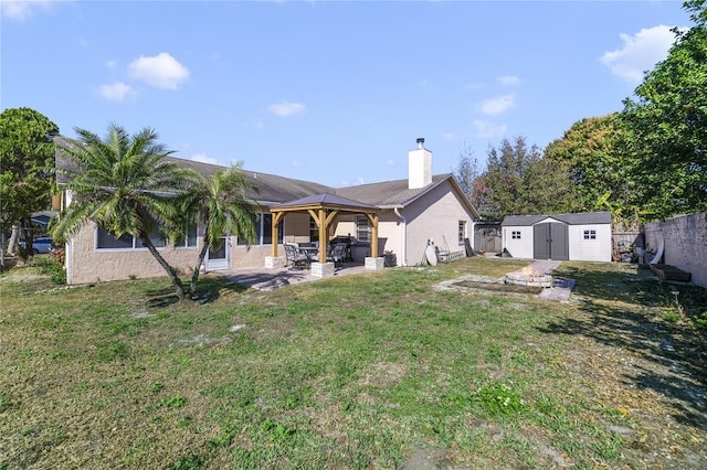 back of property with a gazebo, a patio area, a shed, and a lawn