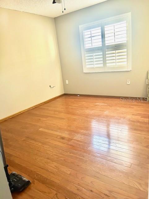 2537 Lanier Rd, Kissimmee, FL 34744 - empty room with light wood-type flooring, a ceiling fan, a textured ceiling, and baseboards